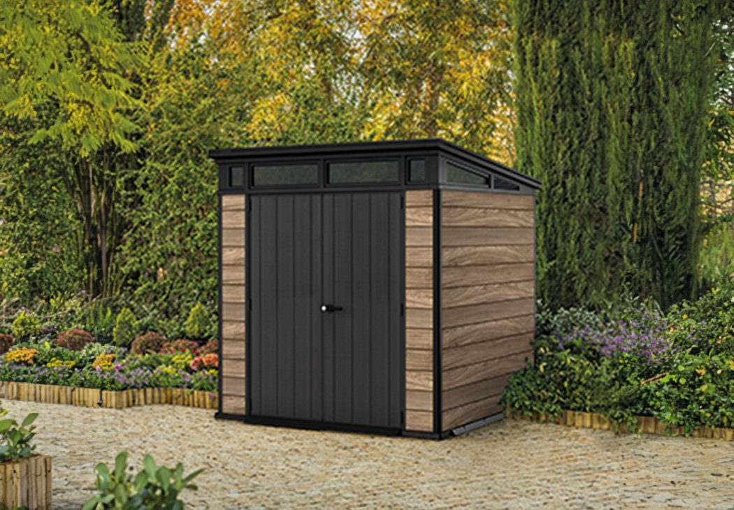 Keter Signature Plastic Oak Pent shed surrounded by trees and shrubs.